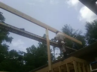 Carpenter setting a ridge beam over a new addition frame — Ice Dam Removal by Roofing Brothers in Port Huron