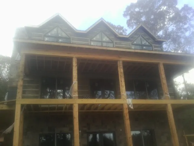 Dormers and porch framing on a large log home under construction — Roof Coating work by our crew in Port Huron
