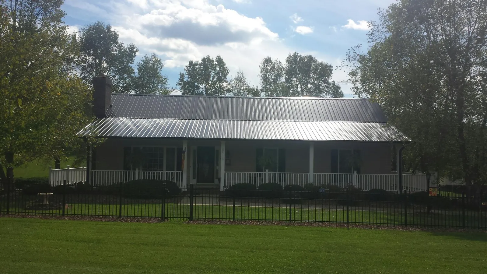 Gray metal roof on a brick ranch with a full width front porch — Gutter Guard Installation work by our crew in Port Huron