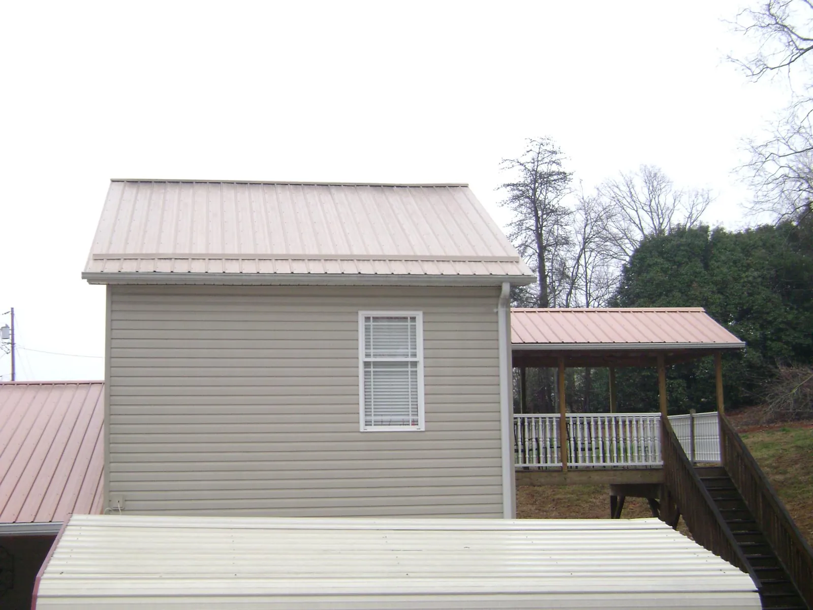 Tan metal roofs on a two story addition and attached porch, from a Roof Replacement job in Port Huron
