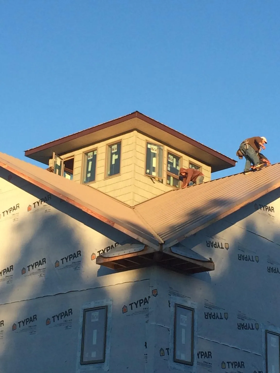 Roofers working around a rooftop cupola on a new metal roof at sunset — Roof Waterproofing in Port Huron by Roofing Brothers